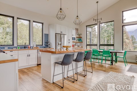 A kitchen with white cabinets and a wooden island with bar stools.