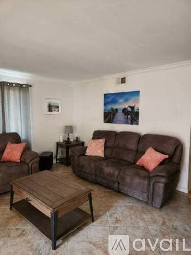 A living room with a brown couch, a wooden coffee table, and a painting on the wall.