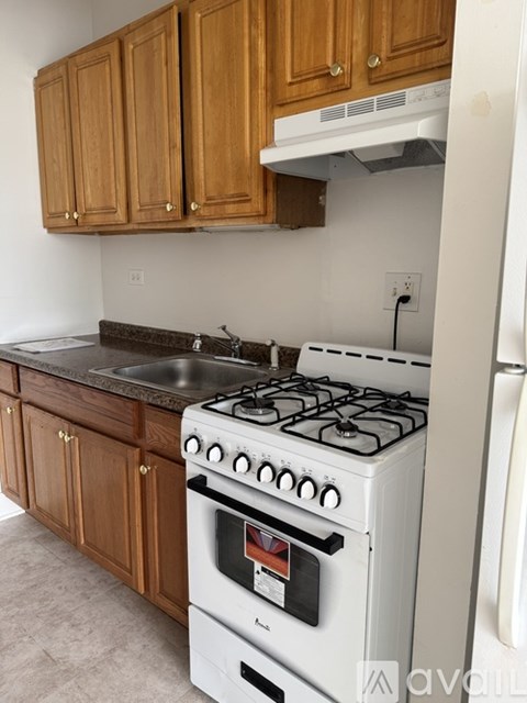 A white gas stove with a white oven is in a kitchen with wooden cabinets.