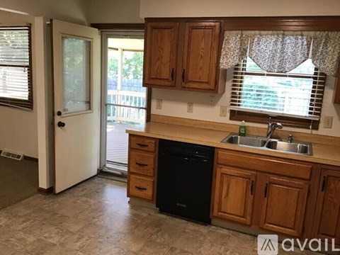 A kitchen with wooden cabinets and a black dishwasher.