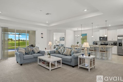 A modern living room with a grey sofa set and a kitchen area in the background.