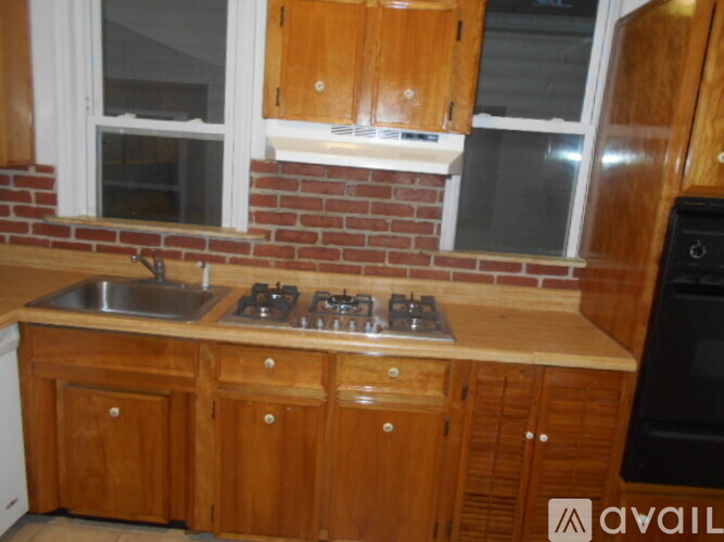 A kitchen with wooden cabinets and a brick wall.