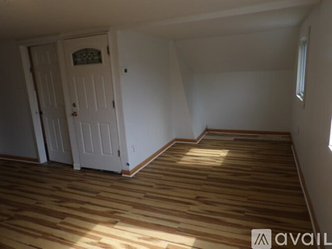 A room with wooden flooring and two doors.