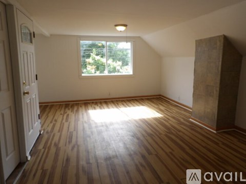 A room with wooden flooring and a window letting in sunlight.