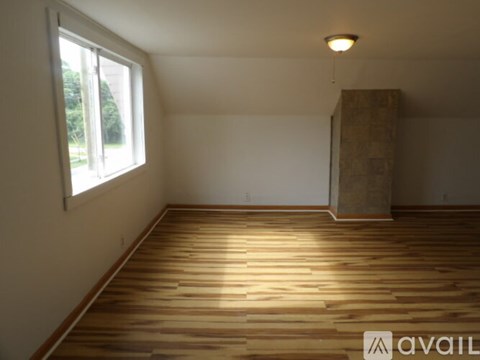 A room with wooden flooring and a window letting in natural light.