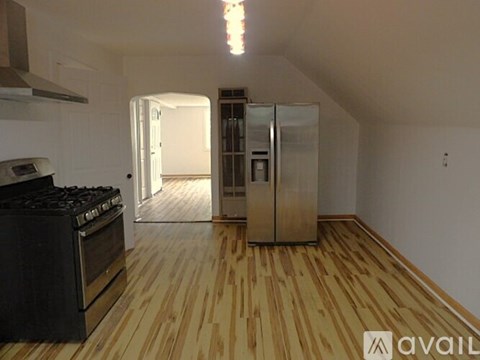 A kitchen with a black stove top oven and wooden flooring.