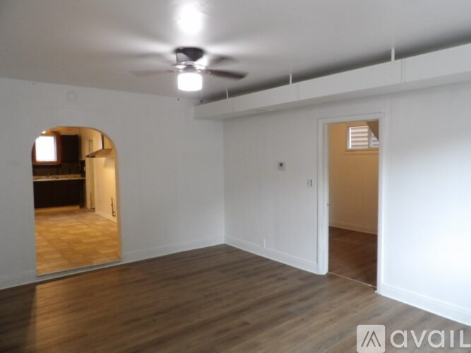 A room with a ceiling fan and wooden flooring.