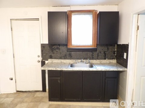 A kitchen with black cabinets and a white door.