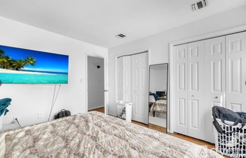 A bedroom with a large bed and a beach scene on the wall.