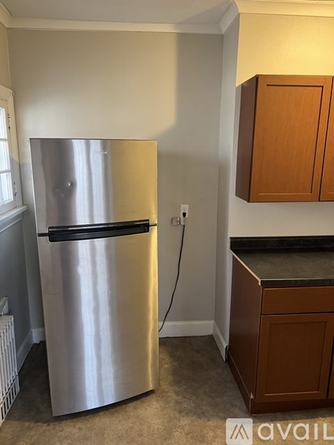 A stainless steel refrigerator in a kitchen with wooden cabinets.