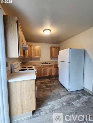 A kitchen with a white refrigerator and wooden cabinets.