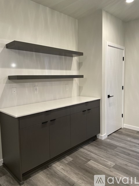 A kitchen with a white counter top and dark brown cabinets.