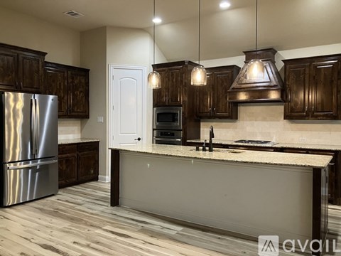 A kitchen with wooden cabinets and a stainless steel refrigerator.