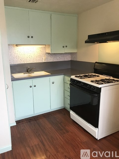 A kitchen with a white stove and light blue cabinets.