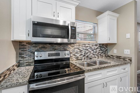 A kitchen with a black stove top oven and a microwave above it.