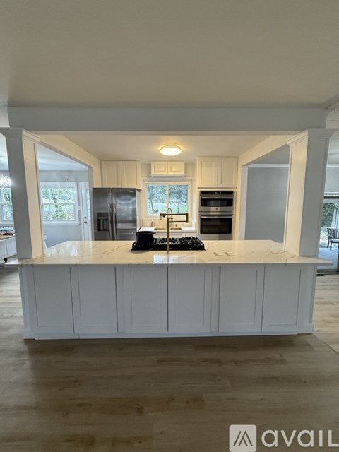 A kitchen with white cabinets and a wooden floor.
