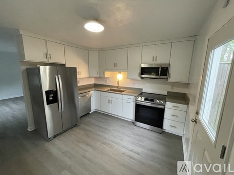 A kitchen with a refrigerator, microwave, oven, and cabinets.