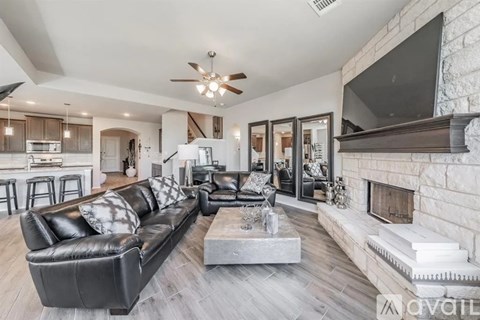 A modern living room with a black leather couch and a fireplace.