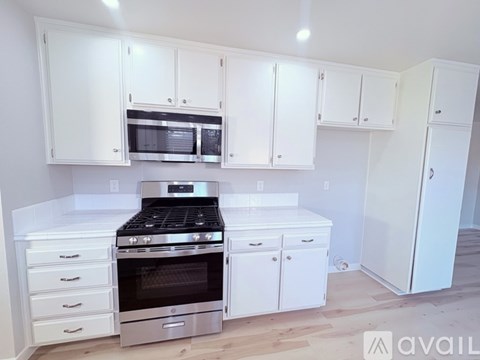 A kitchen with white cabinets and appliances.