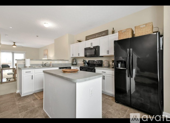 A kitchen with white cabinets and a black refrigerator.