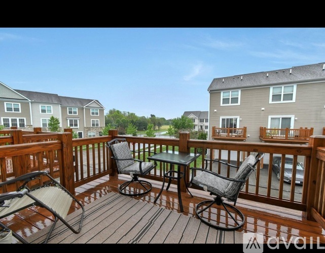 A wooden deck with a table and chairs overlooking apartment buildings.