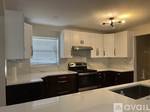 A modern kitchen with white cabinets and a black stove top oven.