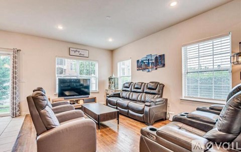 A living room with a large leather couch and a television.