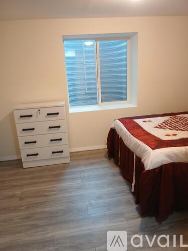 A bedroom with a bed, dresser, and window.