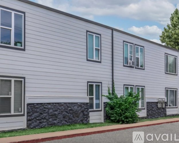 A building with grey siding and multiple windows is shown.