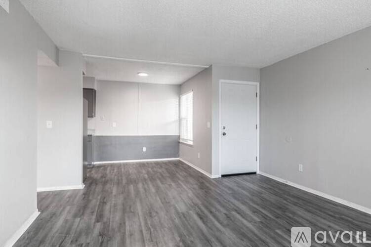 A spacious room with wooden flooring and white walls.