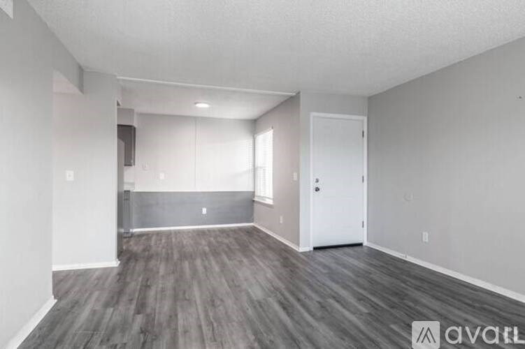 A spacious room with wooden flooring and white walls.
