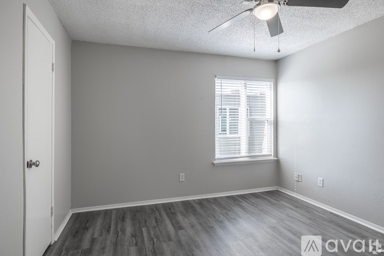 A room with a ceiling fan and a window with blinds.