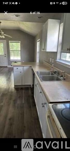 A kitchen with white cabinets and a wooden floor.