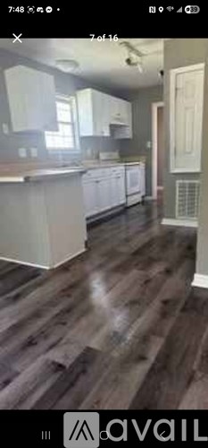 A kitchen with white cabinets and a wooden floor.