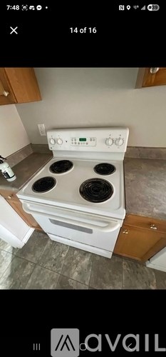 A white stove top oven with four burners is in a kitchen.