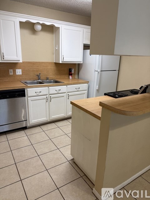A kitchen with white cabinets and a wooden island.