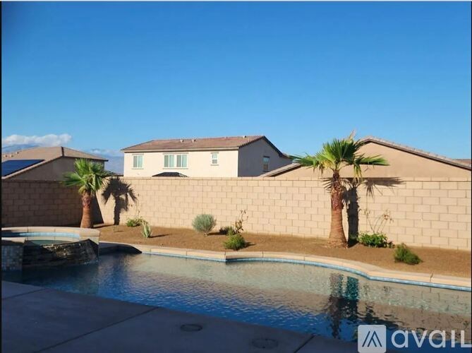 A pool in front of a house with a palm tree.