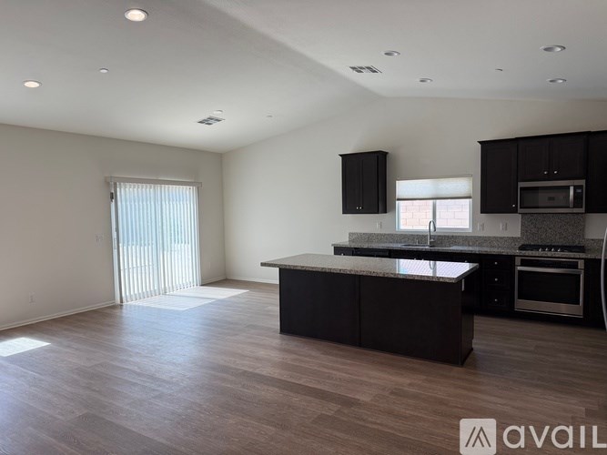 A spacious kitchen with dark wood cabinets and a granite countertop.