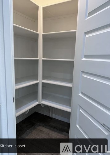 A white kitchen closet with shelves and a door.