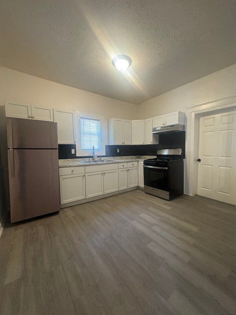 A kitchen with a refrigerator, oven, and cabinets.