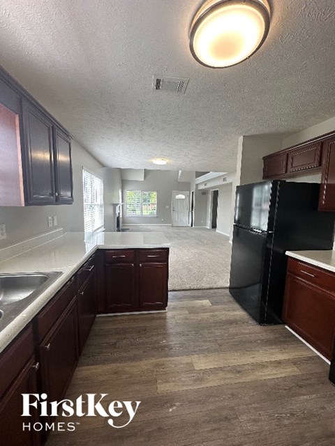 A kitchen with dark wood cabinets and a black fridge.