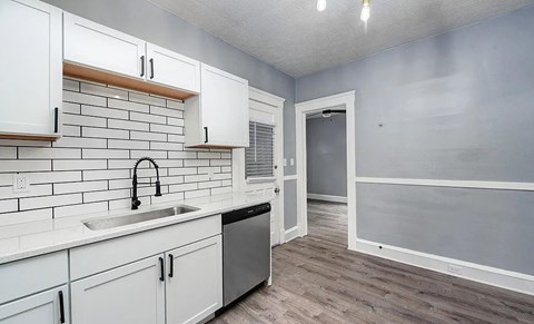 A kitchen with white cabinets and a black faucet.