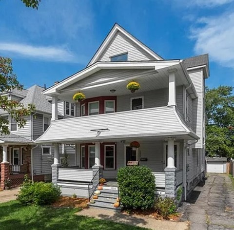 A two-story house with a front porch and a red door.