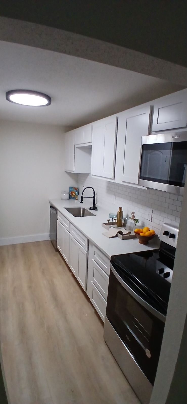 A kitchen with white cabinets and a black stove top oven.