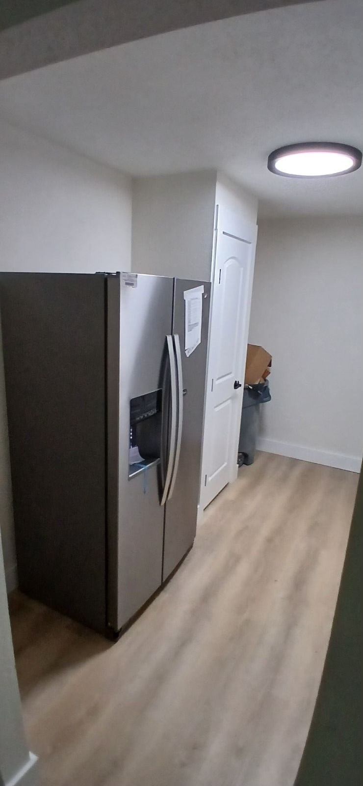 A kitchen with a black fridge and wooden floors.