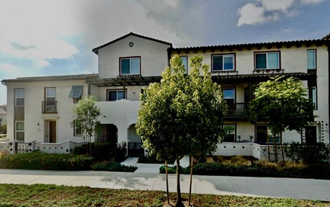A white two-story house with a balcony on the second floor.