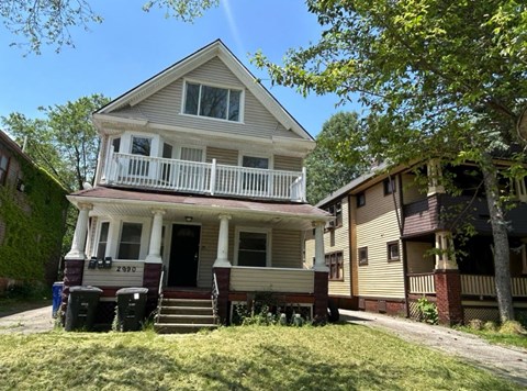 A two-story house with a front porch and a garage door.