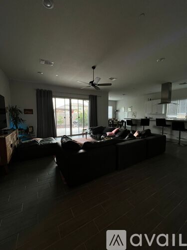 A living room with a black couch and a ceiling fan.