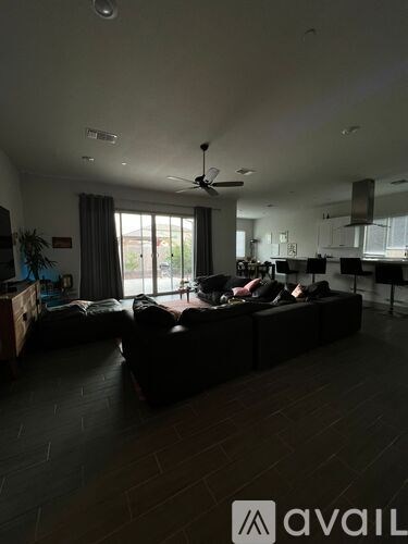 A living room with a black couch and a ceiling fan.