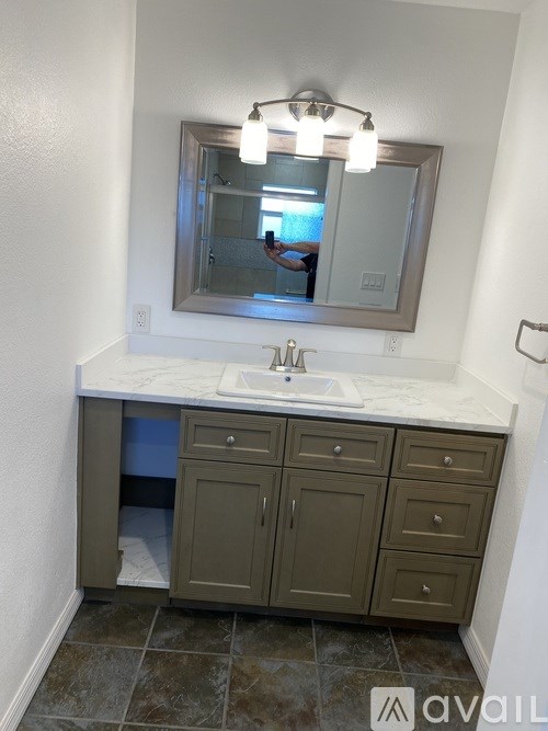 A bathroom with a sink, mirror, and cabinets.